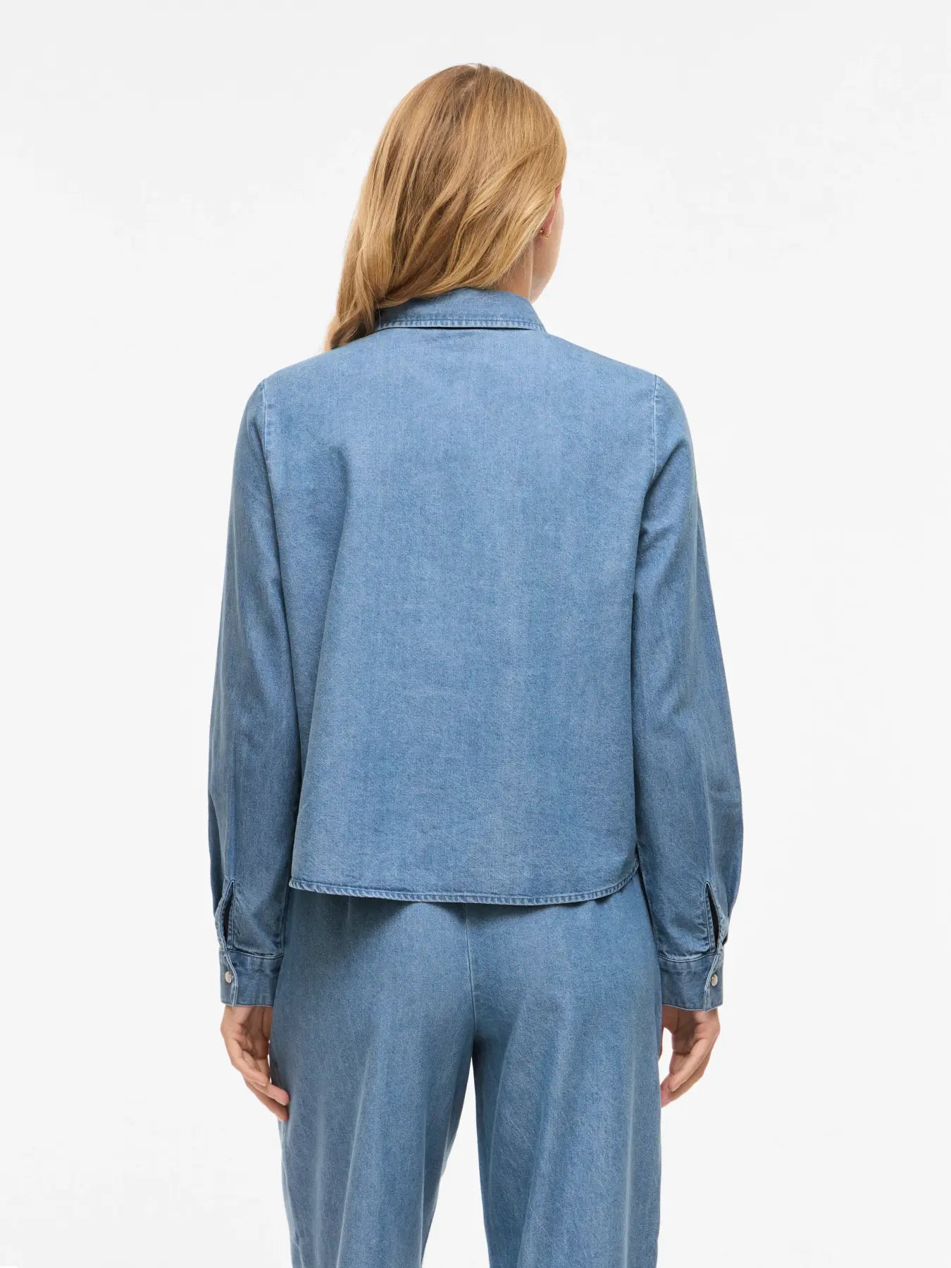 Detalle vista espalda Camisa vaquera azul Vila con lazo en el cuello. Denim fluido, femenina y versátil. Ideal para total look o para combinar a diario. Disponible en Cotton Grey.