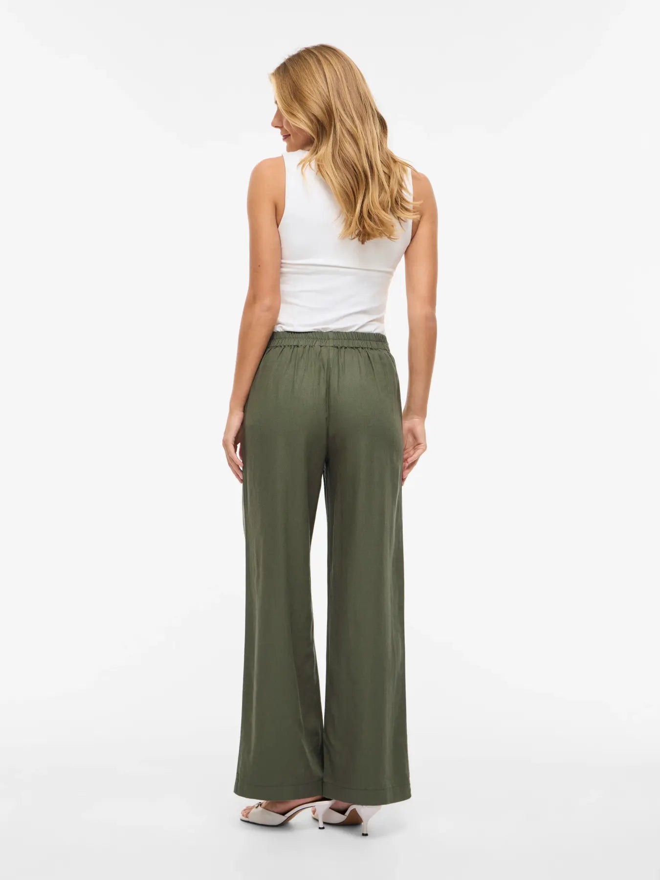 Vista trasera de modelo con pantalon de traje de lino verde kaki en tienda de moda para mujer Vila Cotton grey