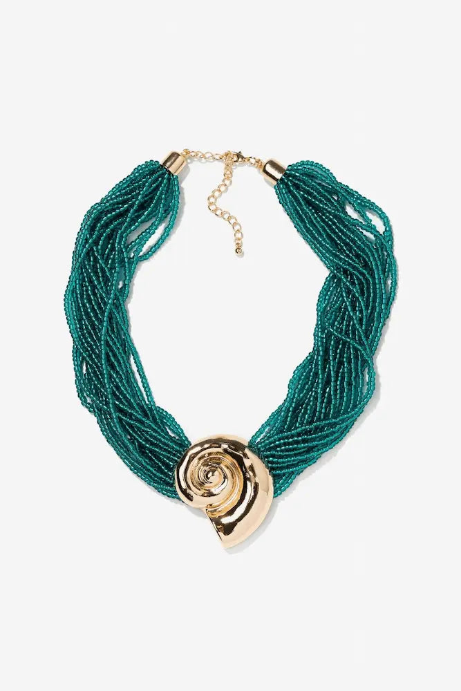 Collar Caracola Turquesa de Vilanova con múltiples hileras de cuentas en color turquesa y adorno central dorado.