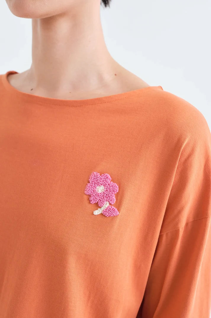 Detalle del parche de flor de la Camiseta Clementine naranja