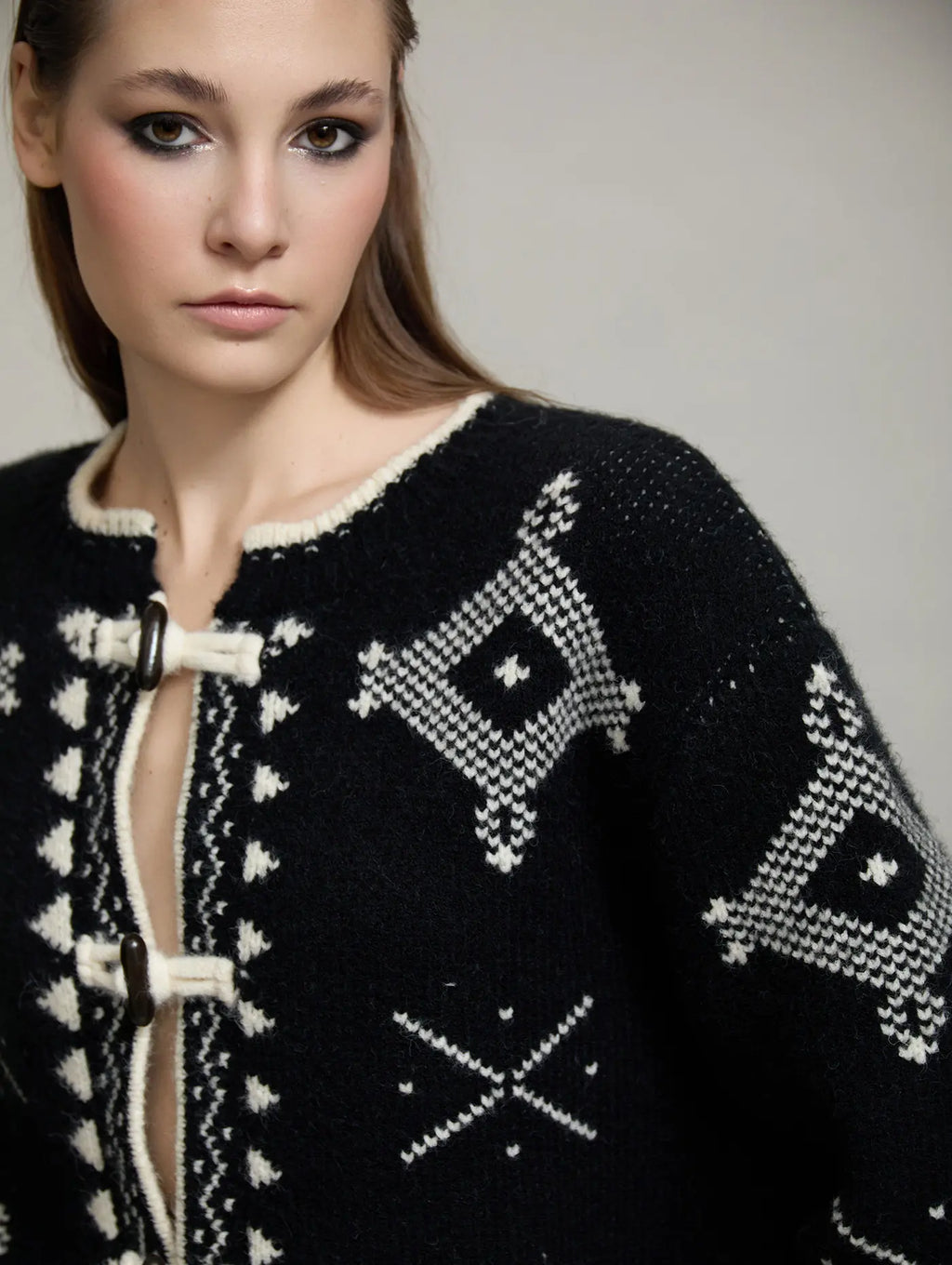 Detalle del cuello redondo y delantero de la chaqueta Zenda de SKATIE en punto negro con motivos jacquard crudos y cierre de alamar.