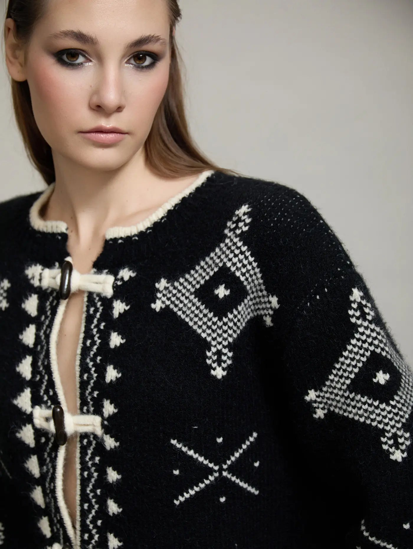 Detalle del cuello redondo y delantero de la chaqueta Zenda de SKATIE en punto negro con motivos jacquard crudos y cierre de alamar.