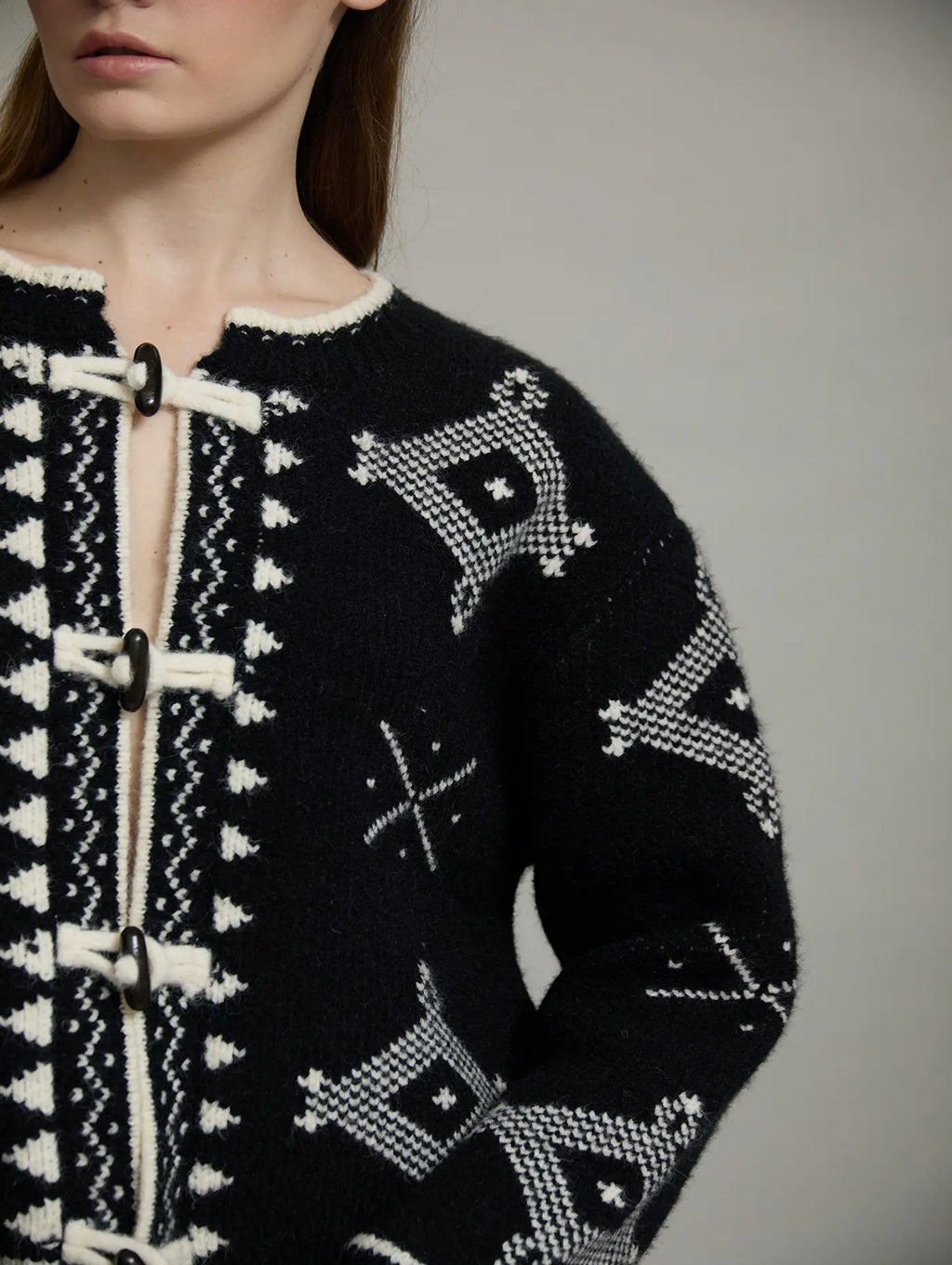 Primer plano del tejido jacquard de la chaqueta Zenda de SKATIE con motivos geométricos en negro y crudo y cierre de alamar.