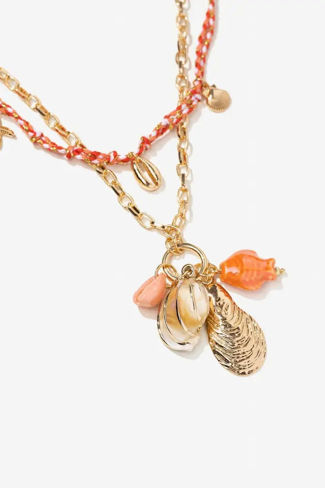 Detalle del collar Coralina de Vilanova con charms de conchas, caracolas y cadena dorada.