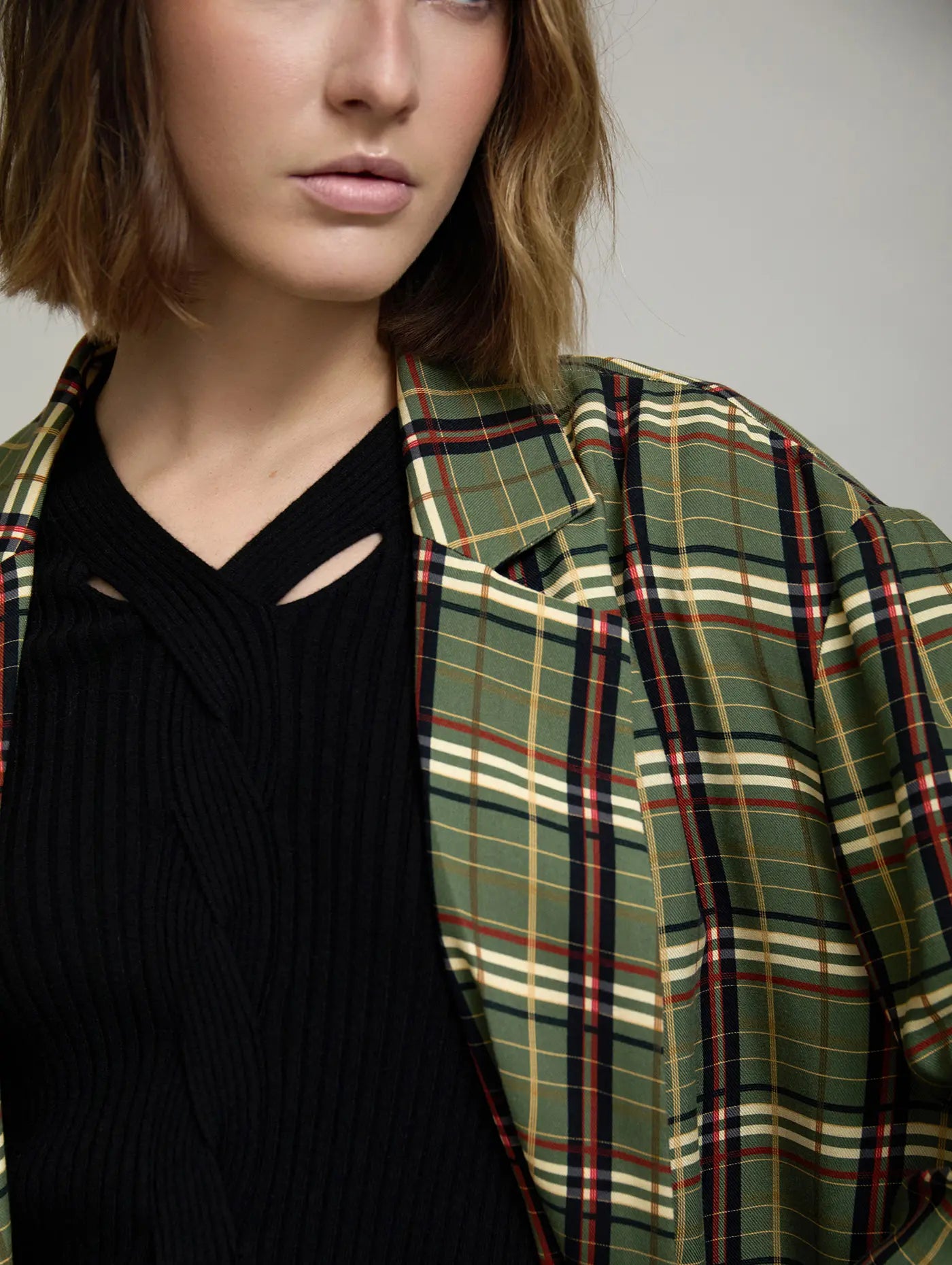 Detalle de la Americana Kensington oversize de cuadros tartán verde, crudo, negro y rojo con solapa amplia, combinada con top negro
