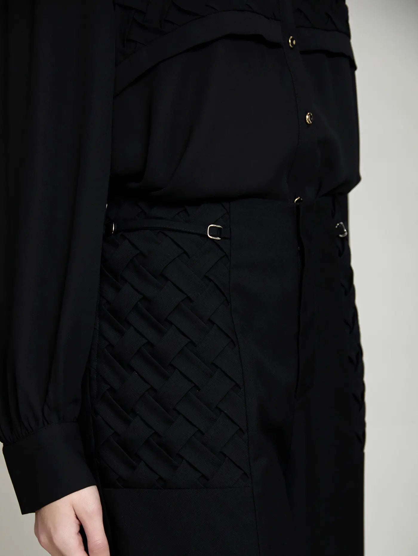 Detalle lateral del Pantalón Celine de SKATIE negro con panel de tejido entrelazado efecto trenzado, tira decorativa y pequeña hebilla metálica en la cintura