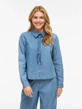 Camisa vaquera azul Vila con lazo en el cuello. Denim fluido, femenina y versátil. Ideal para total look o para combinar a diario. Disponible en Cotton Grey.