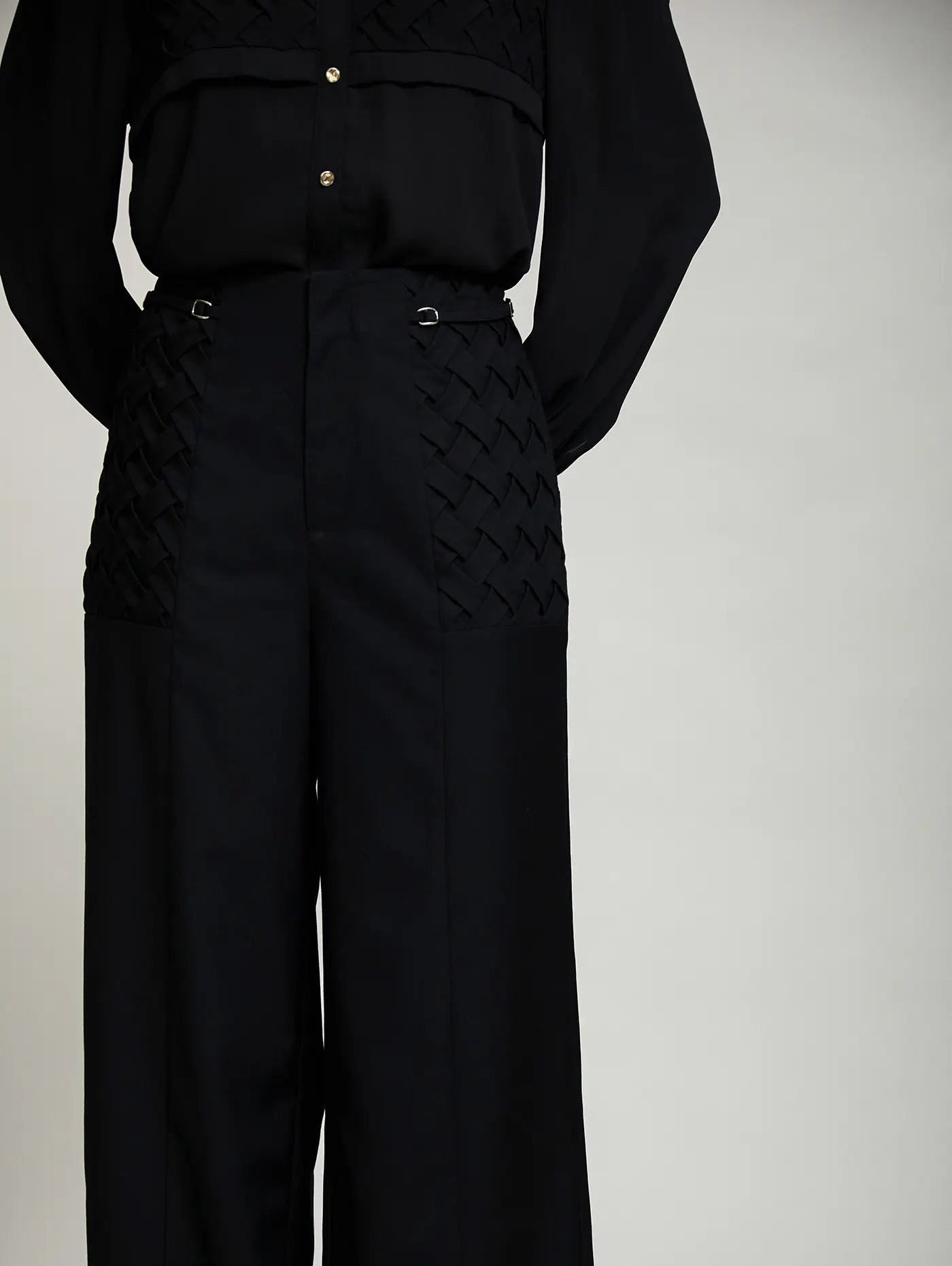 Detalle frontal del Pantalón Celine de SKATIE en negro, de tiro alto, con paneles laterales de tejido trenzado y pequeñas hebillas metálicas en la cintura