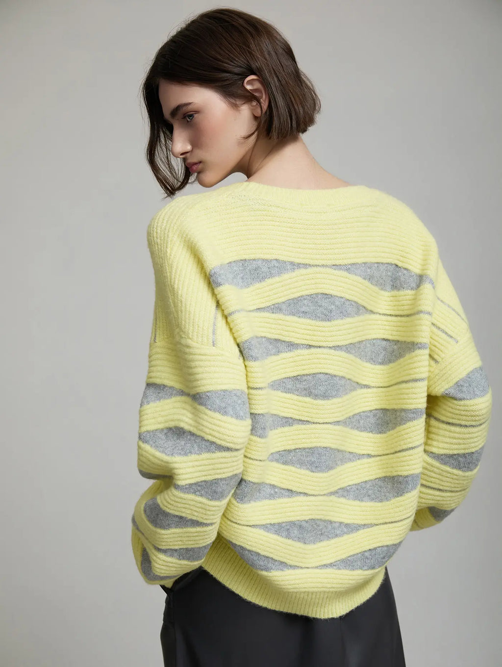 Vista trasera del Jersey Blondie de SKATIE con diseño de punto intarsia de ondas amarillas y grises, hombro caído y silueta amplia