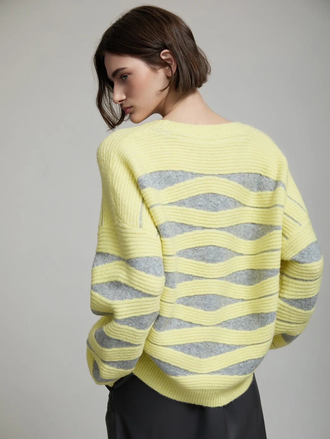 Vista trasera del Jersey Blondie de SKATIE con diseño de punto intarsia de ondas amarillas y grises, hombro caído y silueta amplia