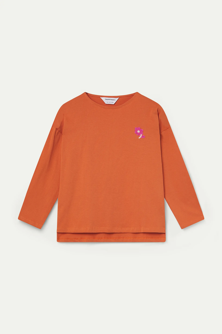 Camiseta naranja con parche de flor combinada en look de mujer