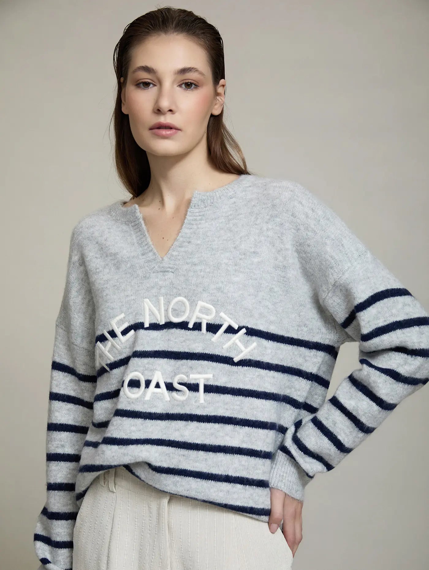 Jersey The North Coast de SKATIE en gris claro jaspeado y azul marino, con escote en V, rayas horizontales y bordado frontal The North Coast en relieve