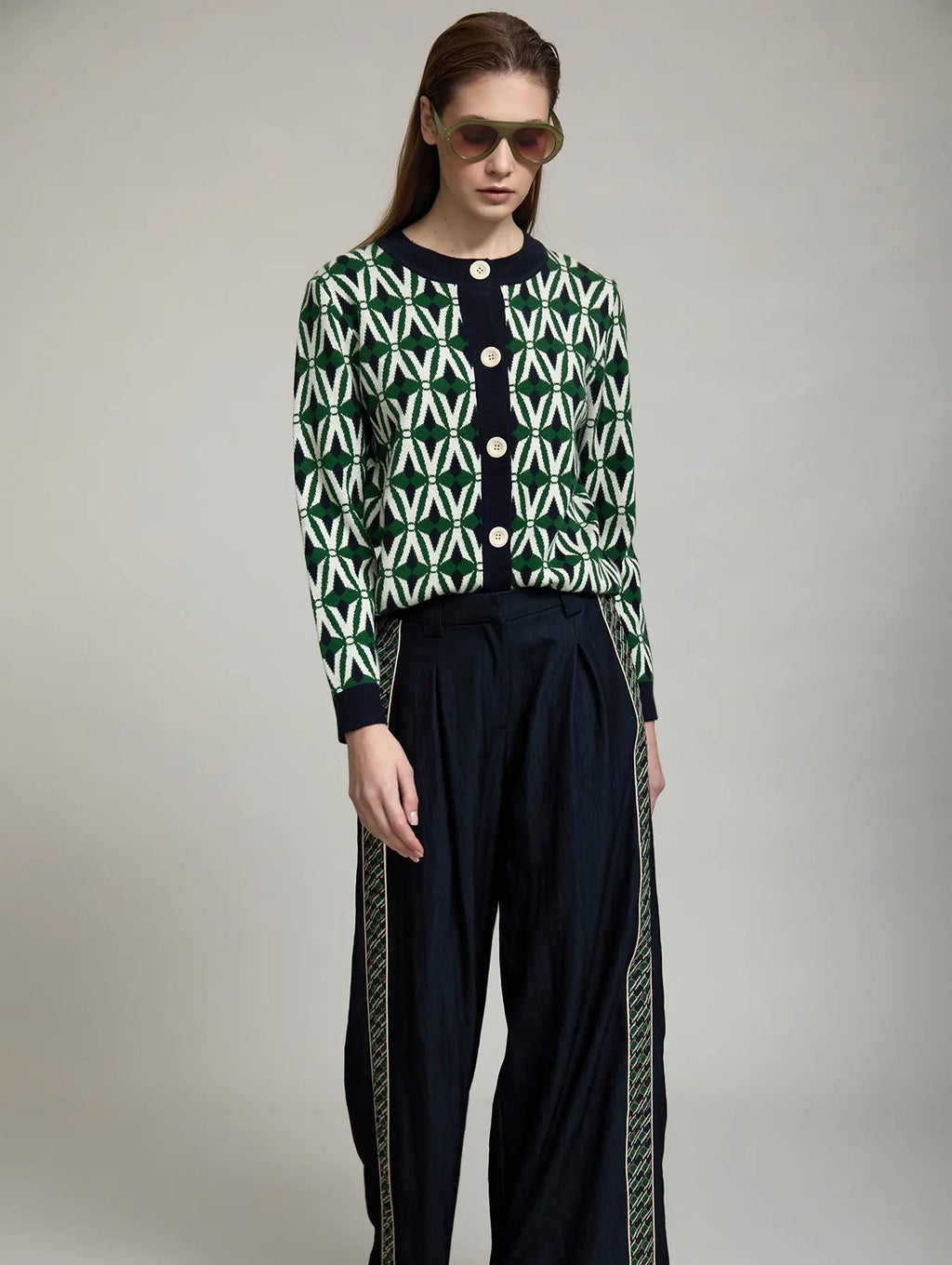 Cárdigan Jacquard Odette de SKATIE de manga larga con estampado geométrico verde, crudo y azul marino combinado con pantalón oscuro de pernera ancha