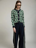 Cárdigan Jacquard Odette de SKATIE de manga larga con estampado geométrico verde, crudo y azul marino combinado con pantalón oscuro de pernera ancha