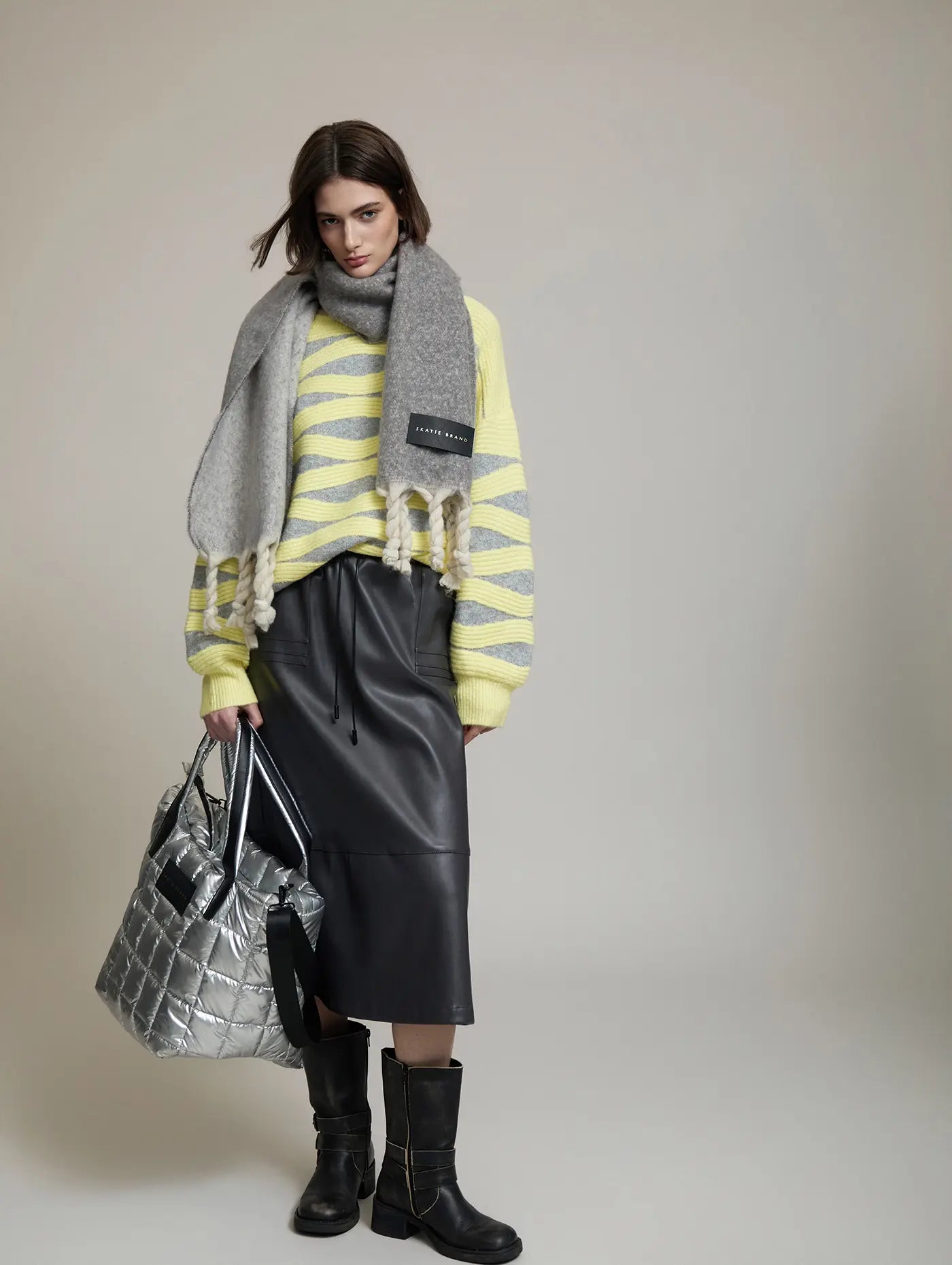 Look con Falda Artic de SKATIE de polipiel gris oscuro combinada con jersey de punto amarillo y gris