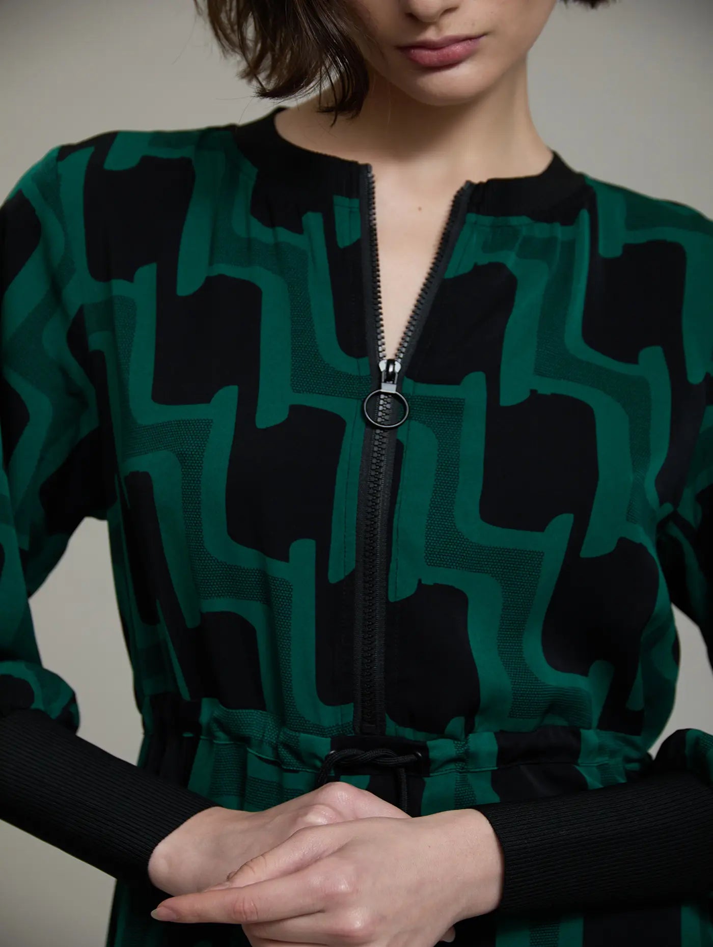 Detalle frontal del vestido midi Sylvie de SKATIE con cremallera negra y tirador de aro, cuello redondo y estampado retro verde y negro