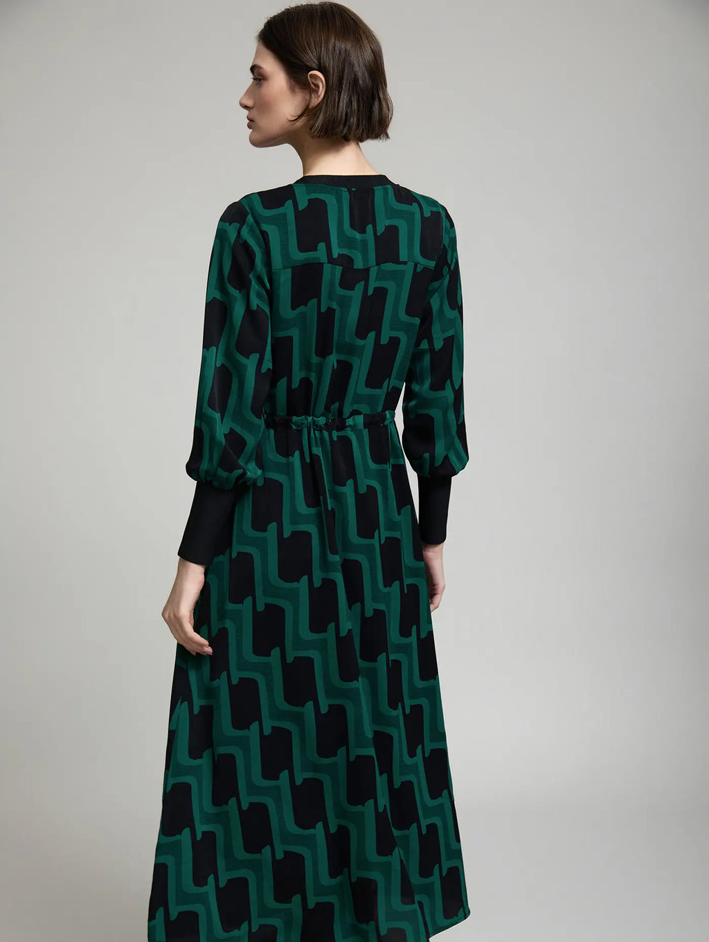Vista trasera del vestido midi Sylvie de SKATIE con estampado geométrico verde y negro, cintura ajustada con cordón y falda larga fluida