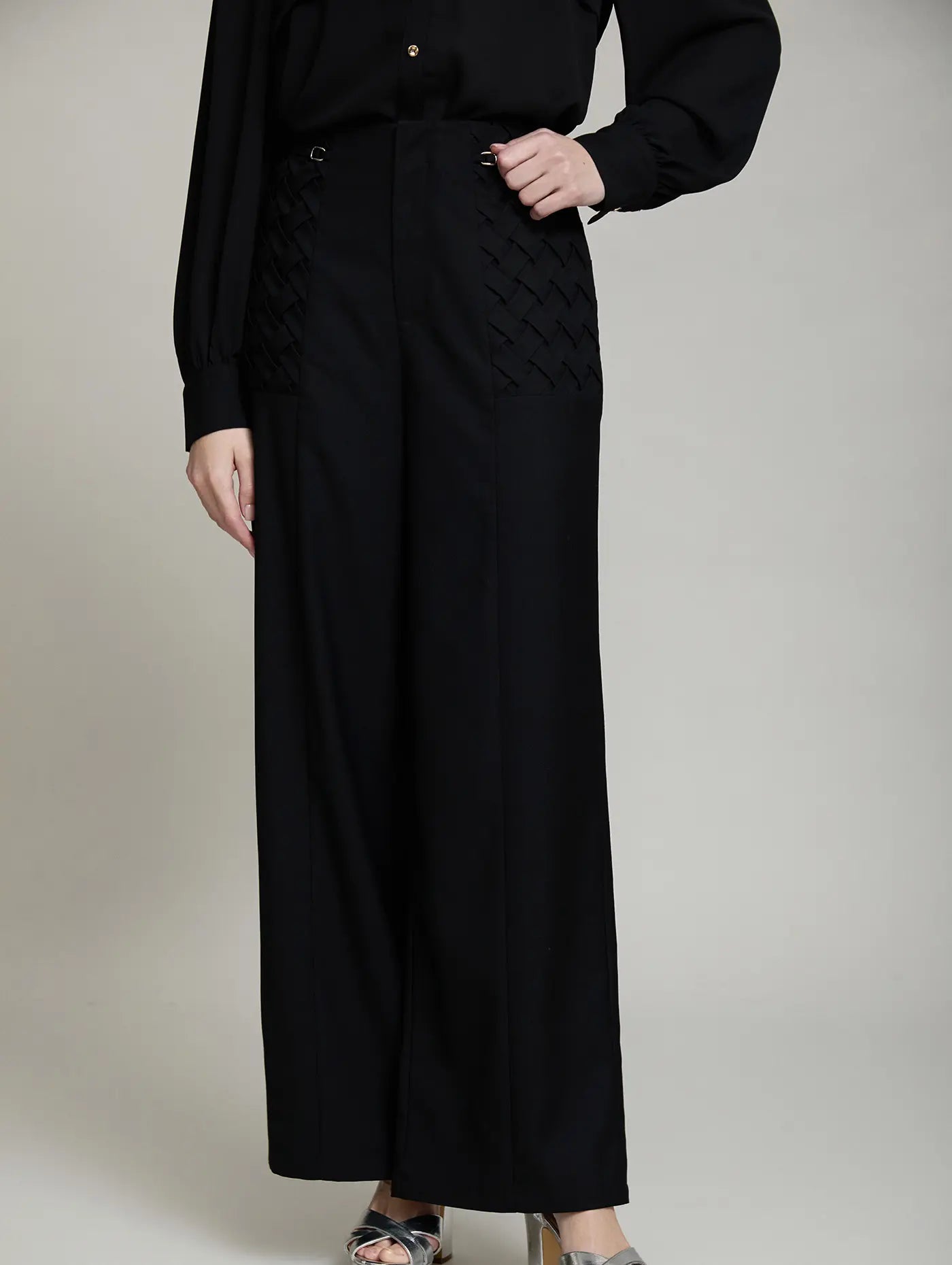 Vista frontal del Pantalón Celine de SKATIE negro de tiro alto y pernera ancha con detalles de tejido entrelazado y hebillas metálicas laterales

