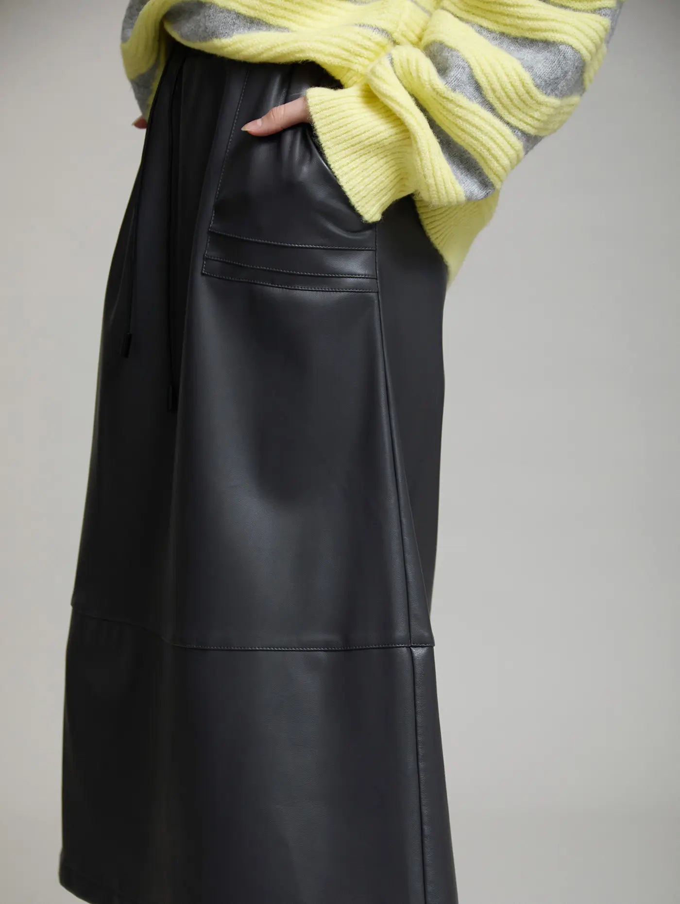 Vista lateral de la Falda Artic de SKATIE de polipiel gris oscuro con bolsillo delantero y corte midi