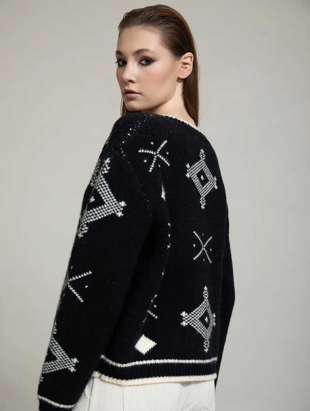 Chaqueta Zenda de SKATIE vista de tres cuartos por detrás, con punto jacquard negro y crudo, manga larga y ribetes en contraste.