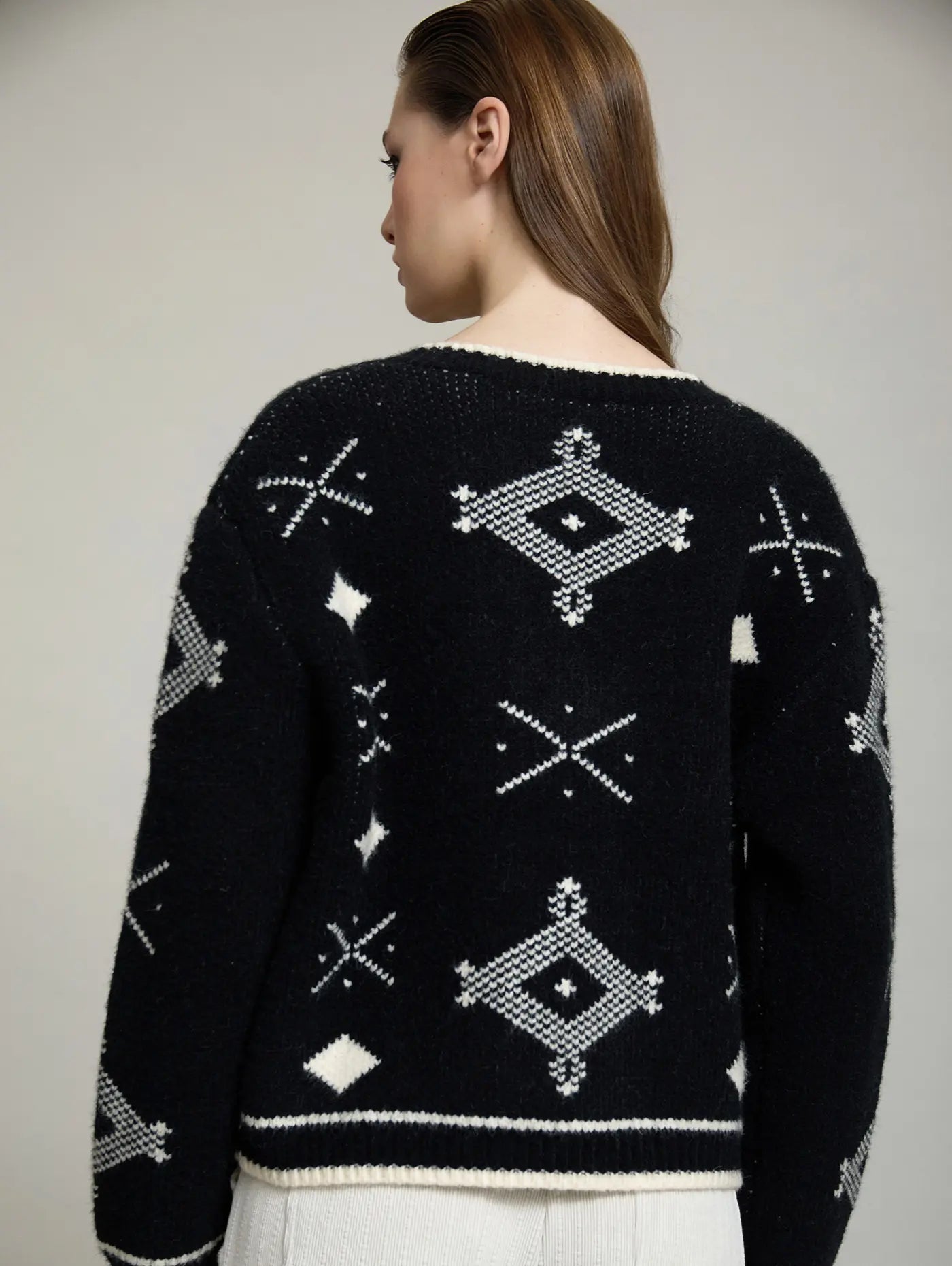 Vista trasera de la chaqueta Zenda de SKATIE en punto jacquard negro y crudo con motivos geométricos distribuidos por espalda y mangas.
