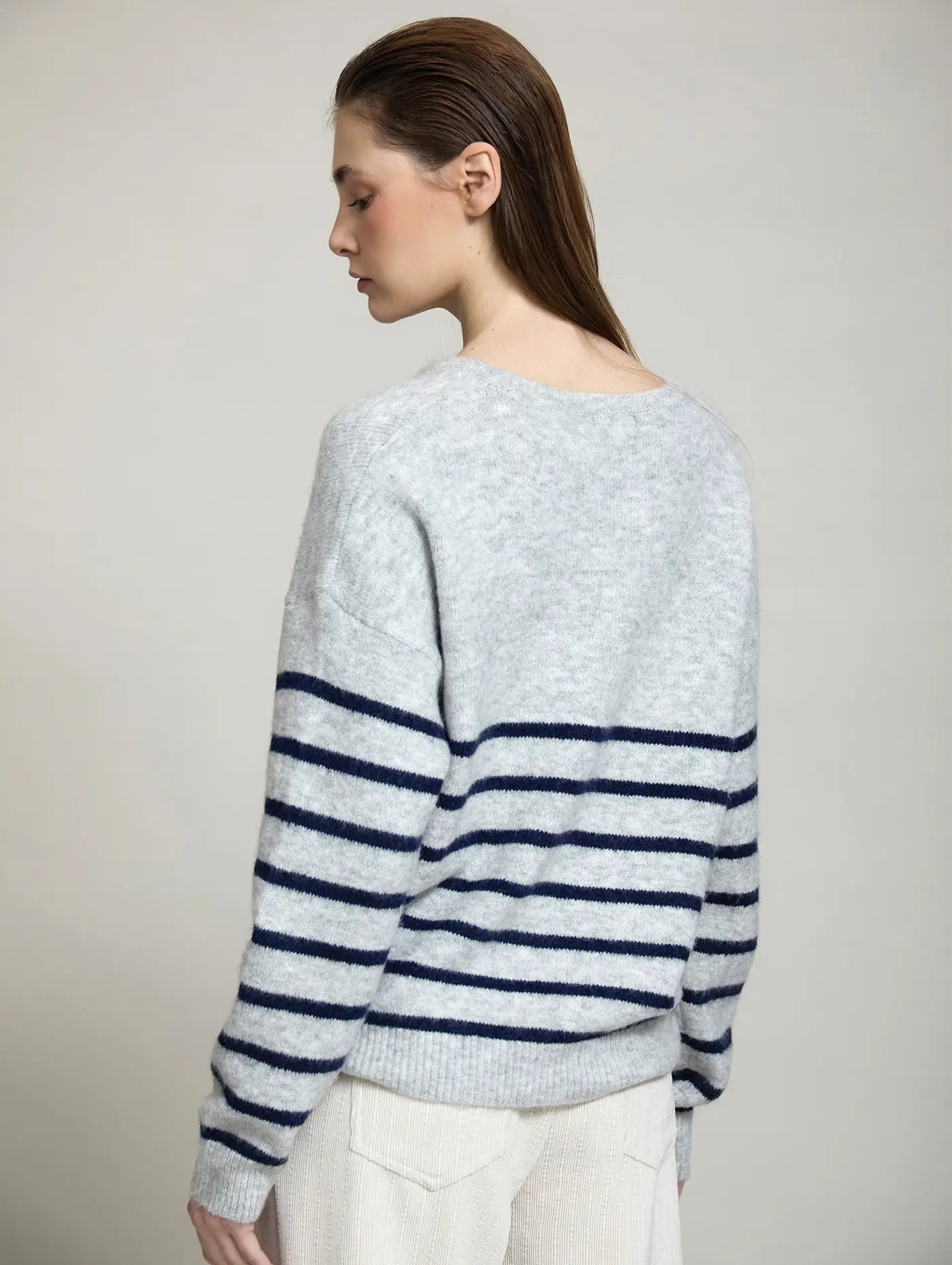 Vista trasera del Jersey The North Coast de SKATIE en gris claro jaspeado, con corte relajado, hombros caídos y diseño de rayas horizontales azul marino en cuerpo y mangas