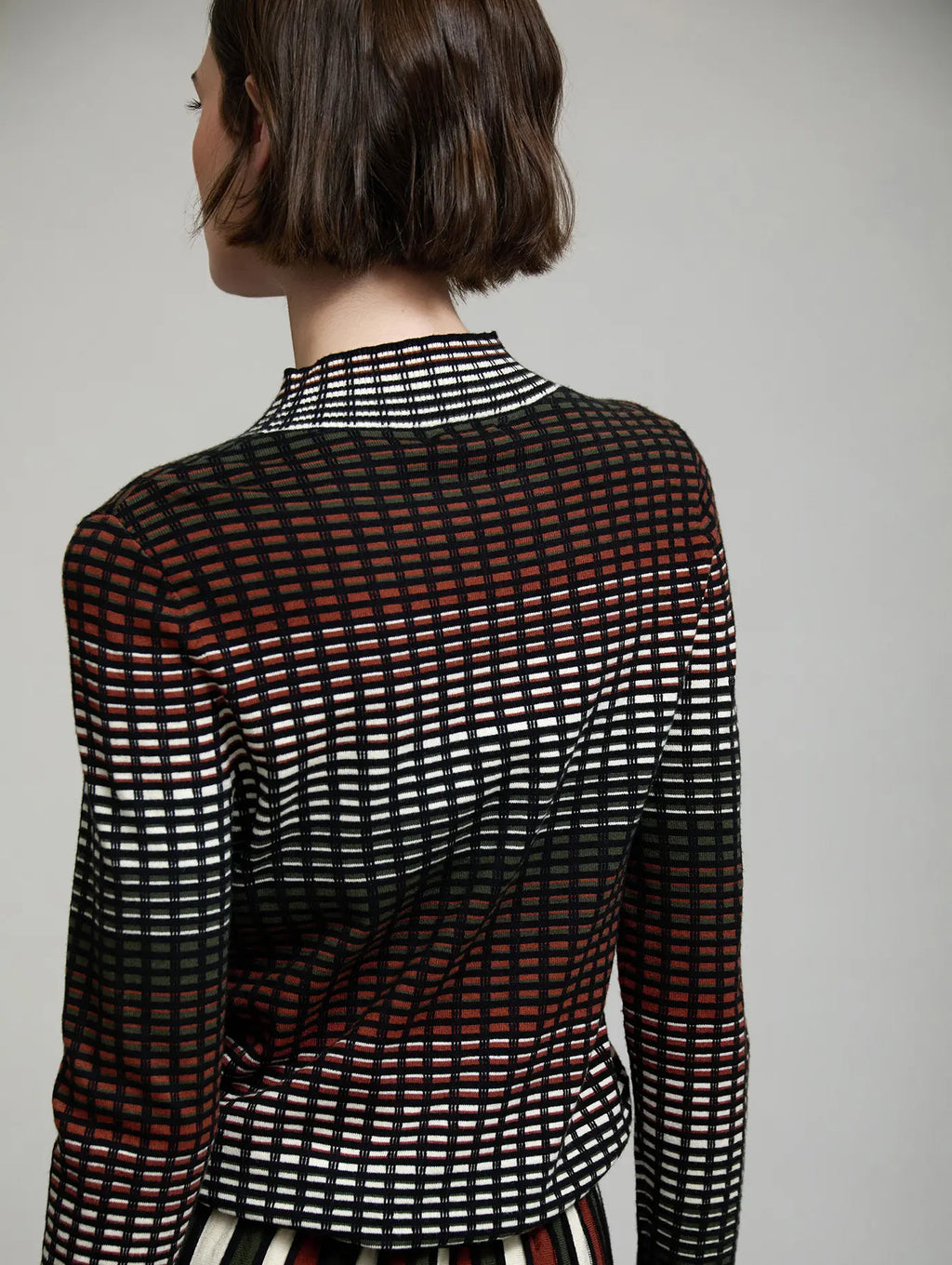 Vista trasera del jersey de punto Margot de SKATIE con diseño de cuadros multicolor en negro, crudo, verde oliva y teja