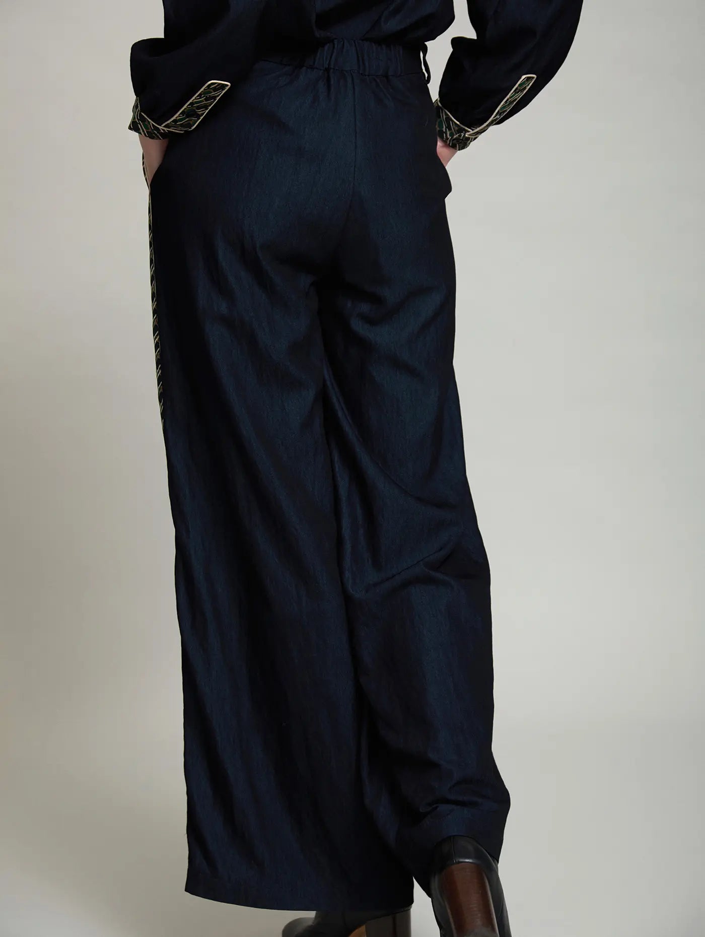Pantalón Margot de SKATIE azul marino visto por detrás, con pernera extra ancha, cintura elástica trasera y detalle de banda estampada en los laterales